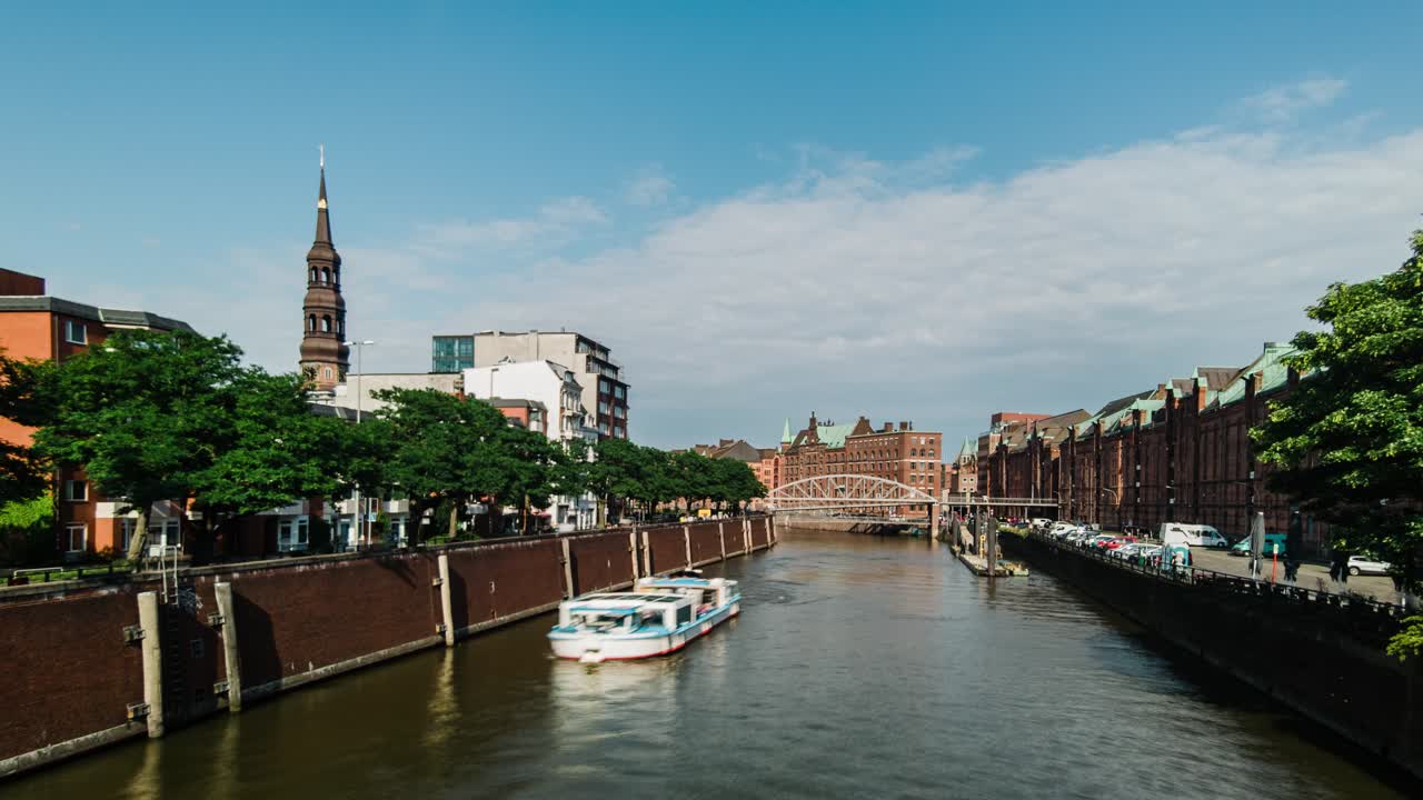 Timelapse of a tourist ferry navigating nikolaifleet canal in hamburg, germany, with st. Nikolai memorial visible in the background