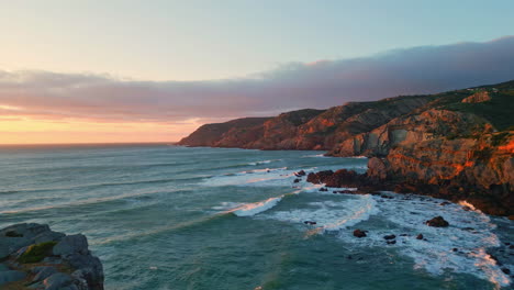 penhascos vulcânicos encontrando o pôr-do-sol oceano vista aérea. mar espumante litoral ondulante