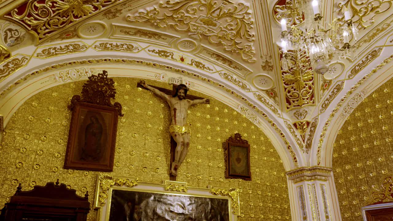 Interno di chiesa cattolica ornata con decorazioni dorate e crocifisso sull'altare all'interno di un tempio storico a Cholula Puebla Messico