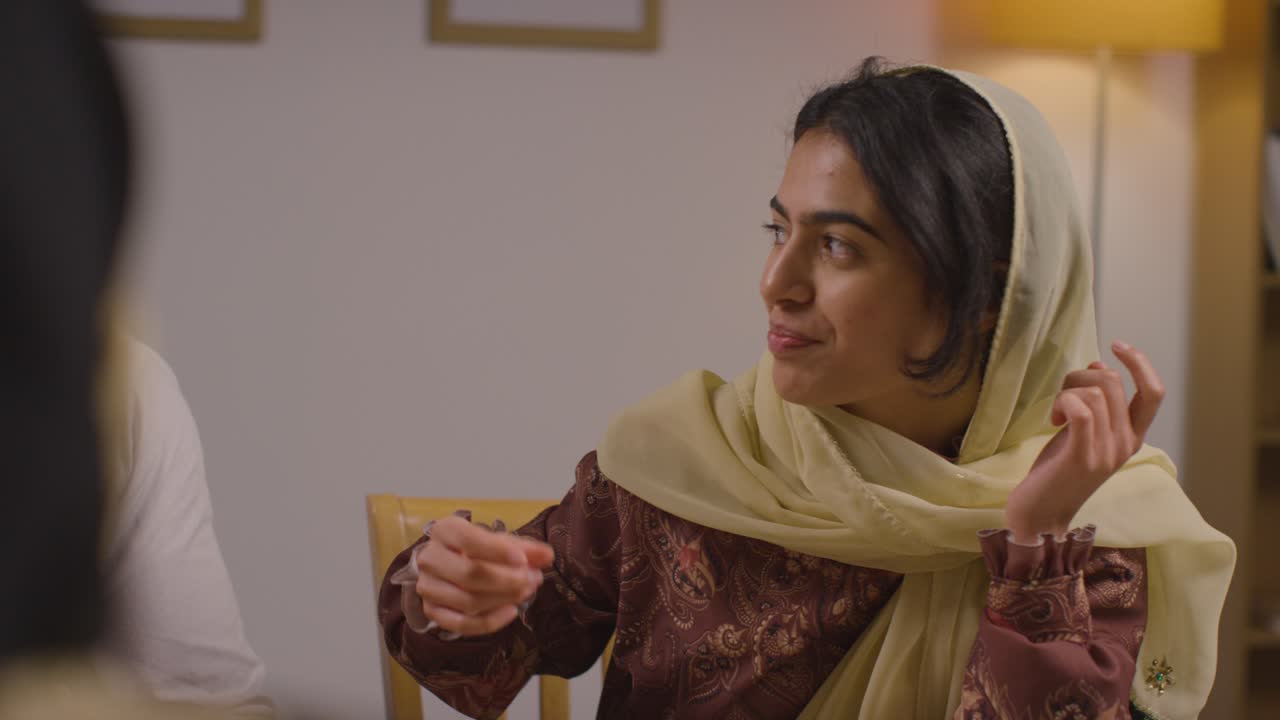 familia musulmana sentada alrededor de una mesa en casa comiendo para celebrar el eid 1