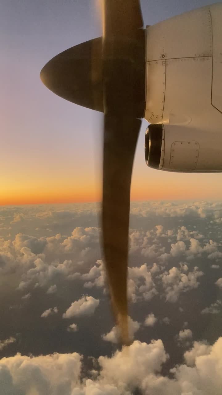 Filmato verticale da telefono fuori dal finestrino di un aereo a elica sopra le nuvole al tramonto