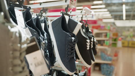 close-up view of black shoes hanging on a rack in a mall with a blurred background. this video highlights the footwear display in a retail environment, showcasing various styles of shoes