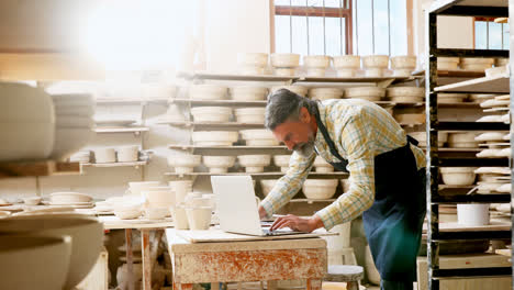 Thoughtful-male-potter-working-at-laptop-4k