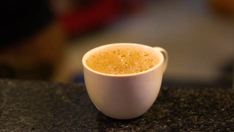 a cup of hot milk tea ready to serve in a restaurant in pakistan - traditional pakistani queta tea - close-up steaming hot coffee or tea cup on the saucer,