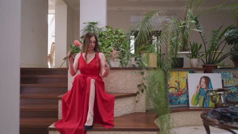 mujer elegante en vestido rojo posando en las escaleras