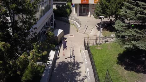 Aerial-Drone-Shot-Following-Behind-a-Young-Adult-Male-Parkour-Free-Runner-Flipping-and-Jumping-Down-Flights-of-Stairs