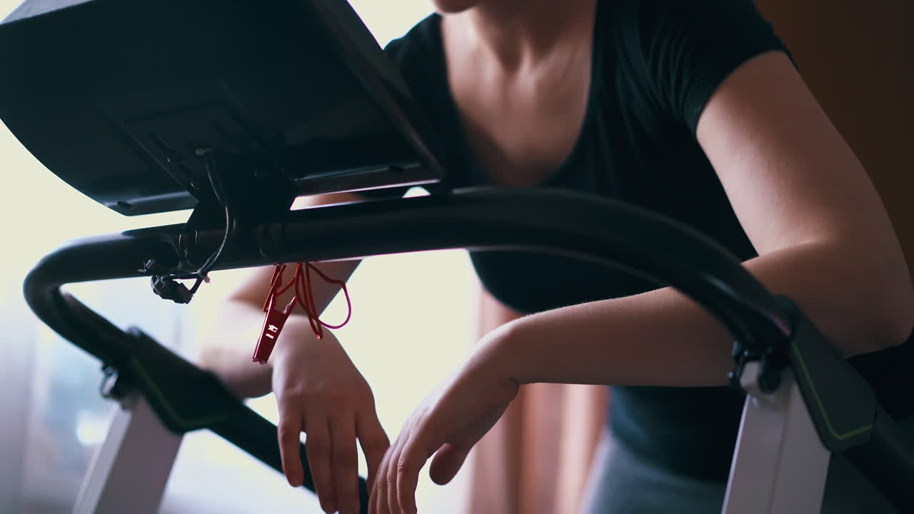 피곤 한 여자 는 훈련 후 트레드밀 손잡이 에 기대어 있다