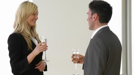 una mujer de negocios y un hombre de negocios celebrando un éxito con champán.