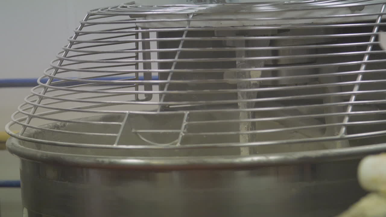 cámara lenta de la mezcladora industrial de tortas girando los ingredientes para hacer una masa