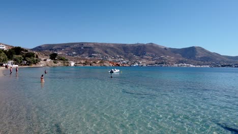 aerial of woman walking by the krios beach seaside, paros