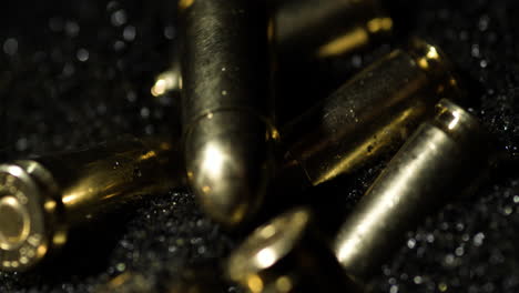 macro detail shot of 9×19mm parabellum bullets in slow motion falling on gunpowder