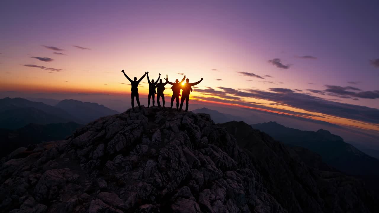 Silhouetted group atop a mountain at sunset, captured from a low angle