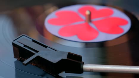 black vinyl record with red hearts spinning on dj turntable.  antiquarian record player. needle playing record album popular music equipment for 60s, 70s, 80s, 90s. love concept close up, macro