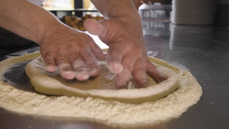 Close-up-view-of-a-chef-hands-kneading-pizza-dough-on-a-restaurant-kitchen-countertop