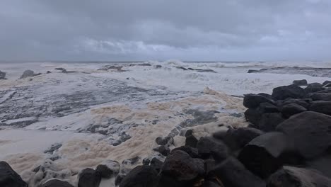 people with umbrella at snapper rocks amidst cyclone alfred and strong waves in gold coast, queensland. panning shot