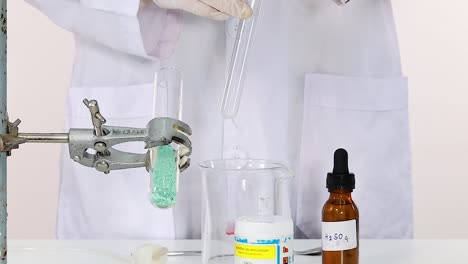 a lab technician transfers liquid between glassware using a pipette in a controlled environment.