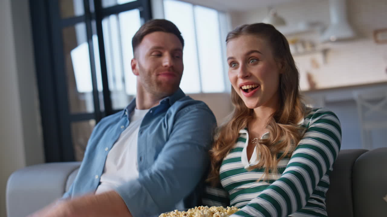 Familie ser tv tæt på i sofaen derhjemme. Kæresten skifter kanal.