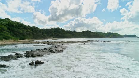 Waves-break-off-the-rocky-coast-in-Nicaragua,-cinematic-establisher,-sunny-day