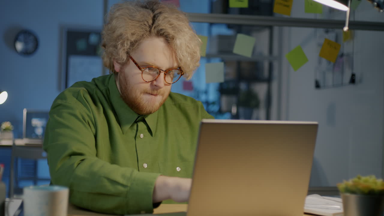Mann arbeitet nachts im Büro am Laptop