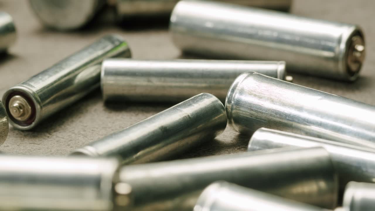 Silver batteries AA and AAA on black background close-up. Double-A battery is a standard size single cell cylindrical dry battery. Batteries are common in portable electronic devices. An AA battery is composed of a single electrochemical cell that may be either a primary battery or a rechargeable ba