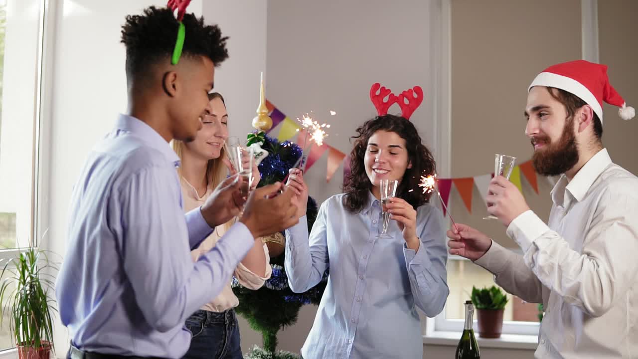 Group of happy office workers toasting for achievements in New Year wearing christmas hats and deer headband, holding Bengal