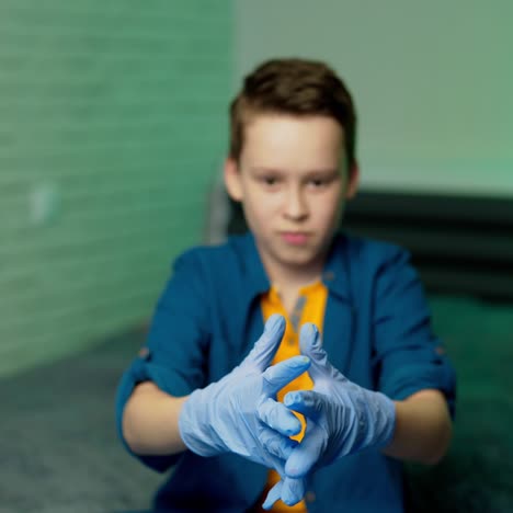 boy wears medical rubber gloves. boy holds hands in rubber gloves in front of camera. stop coronavirus. pandemic. covid-19