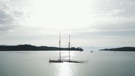 Shipwreck-masts-against-bright-sun-light-and-shimmering-Mediterranean-sea,-Greece