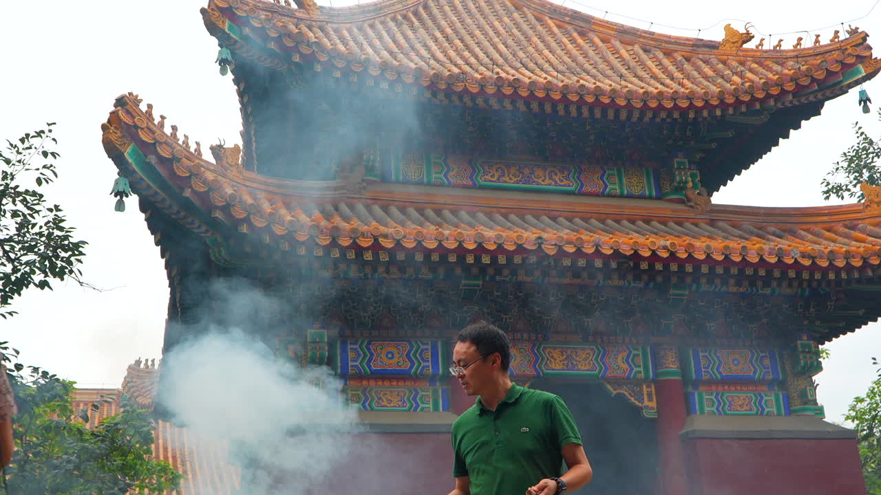 Chinese man leaving an incense stick in a traditional ancient temple. Slow motion