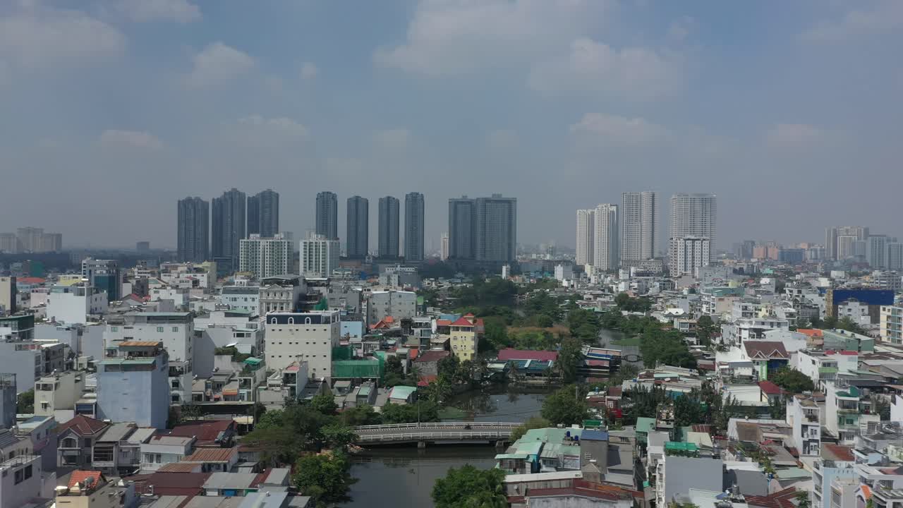 tiro de seguimiento aéreo sobre un área suburbana de alta densidad en un día soleado con edificios, calles, canal, horizonte de la ciudad y cielo azul