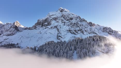 aerial view of fronalpstock's snow-capped peak emerging through a sea of fog, set in the serene landscape of glarus, switzerland.