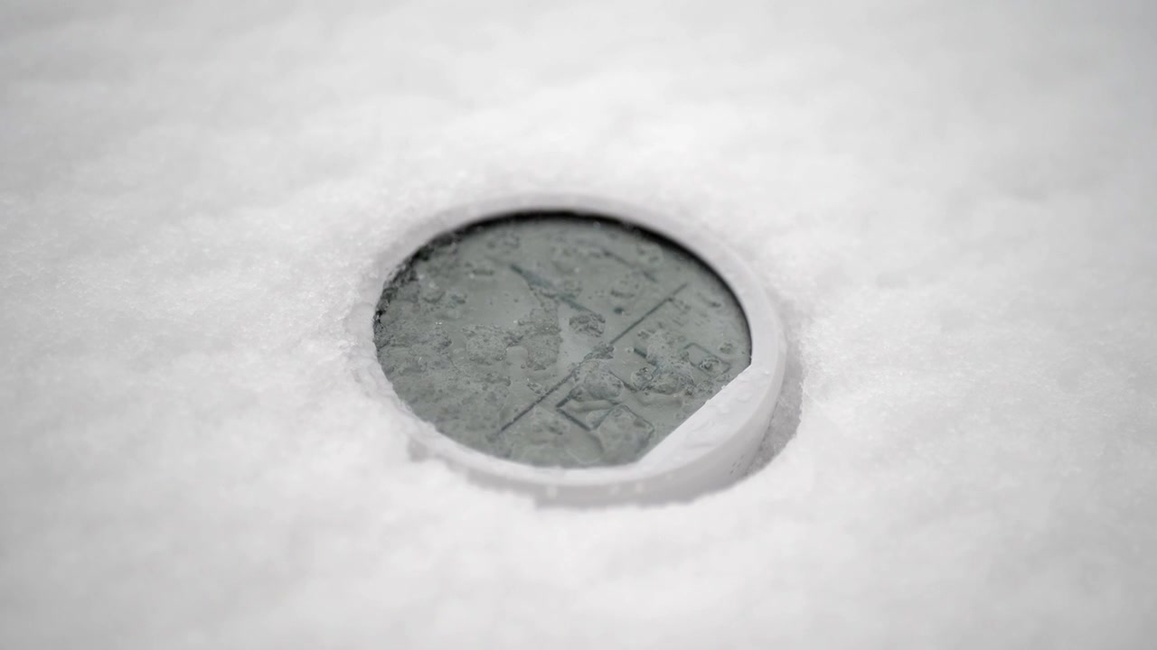 Vecchia moneta di metallo sepolta nella neve bianca fresca.