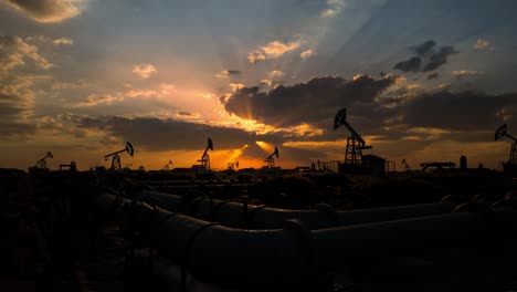 pipeline and working oil pump jacks in a against sunset extracting crude oil. pumping fossil oil is one of the methods of energy generation from renewable energy sources