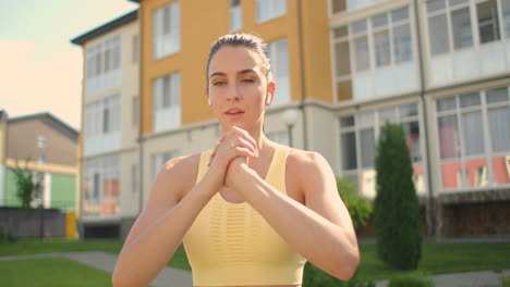 a woman makes lunges on a sidewalk path in a park in an urban environment. slow-motion shooting of a woman in sportswear steps with a lunge