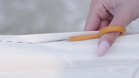 woman's hands cutting plastic sheet with scissors