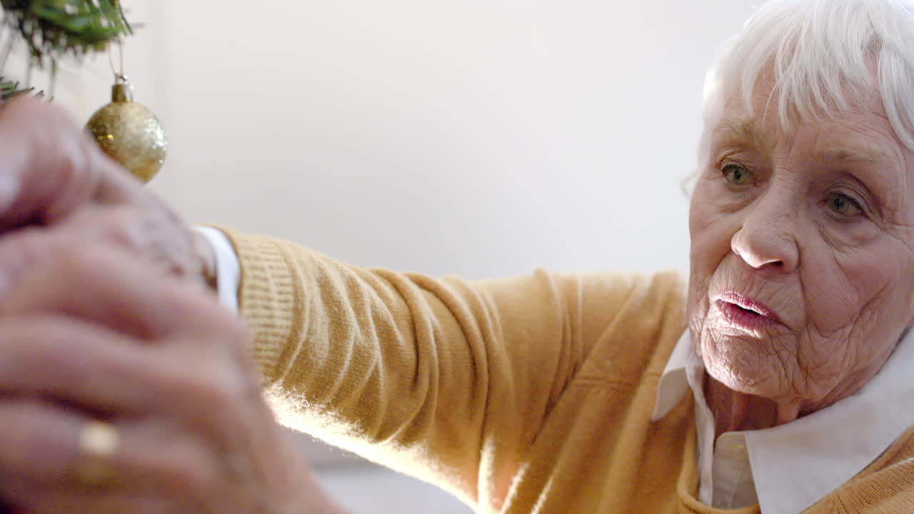 행복한 고위 백인 여성이 집에서 크리스마스 트리를 장식하고, 느린 동작