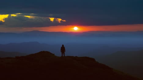 the man standing on the mountain top against the picturesque sunrise. time lapse