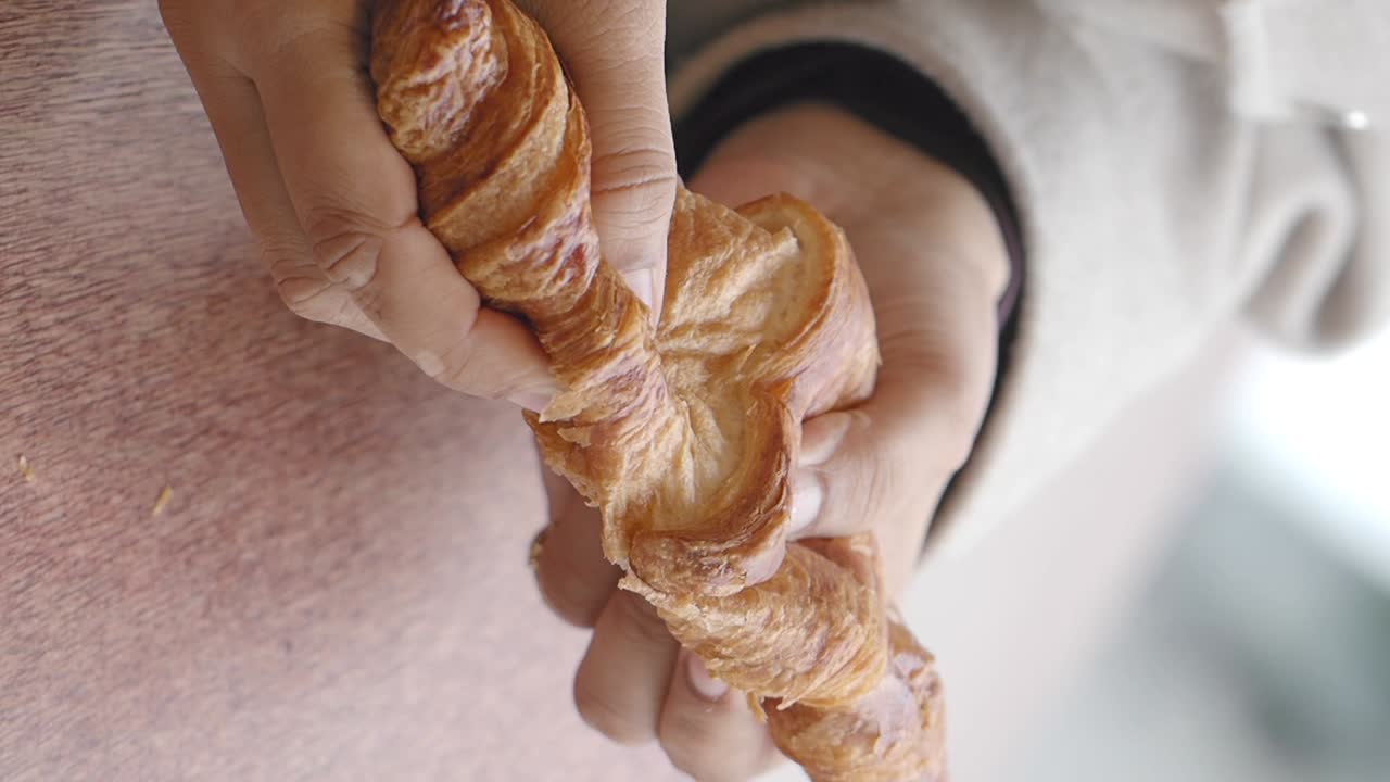 Hands holding and eating a croissant