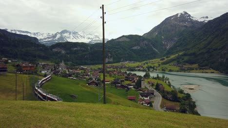 train on railway at lake lungern, swiss alps in background