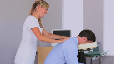 masseuse giving businessman a shoulder massage