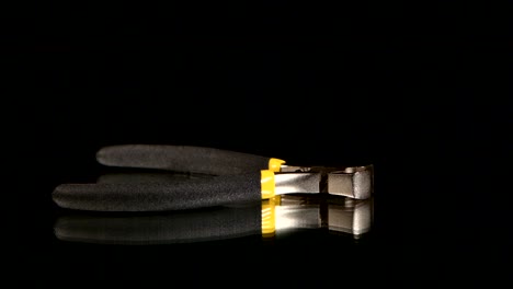 close-up of black and yellow pliers on dark background
