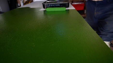 roller brush used in painting table top at the garage with green latex paint