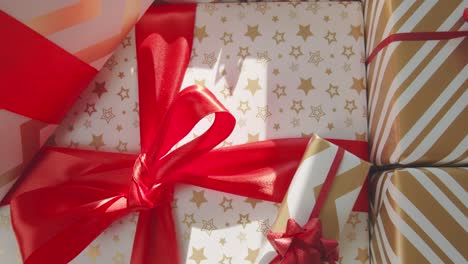 top down over wrapped presents with big red bows with gold and white paper