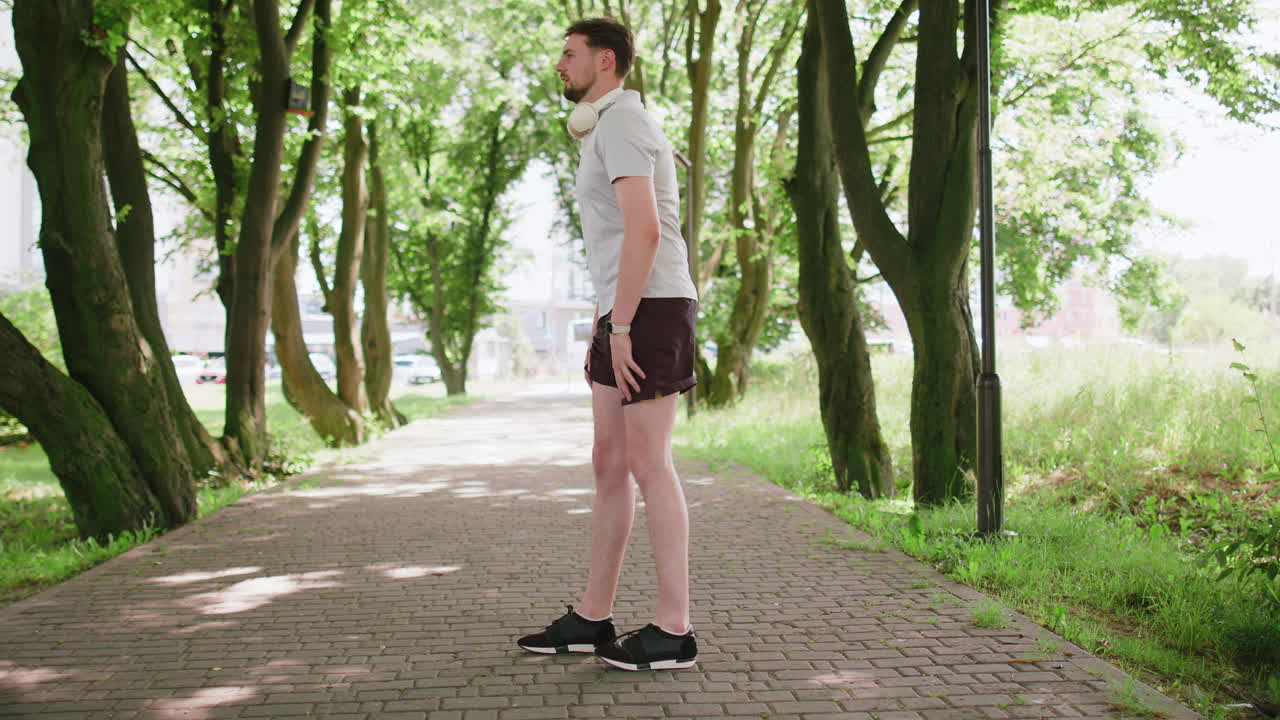 Fitness man in sportswear doing lunges stretching legs on summer park warm up before jogging workout