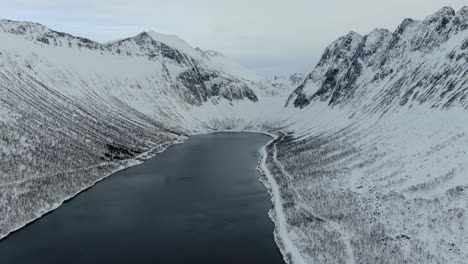 Drohnenansicht-In-Der-Gegend-Von-Tromso-Im-Winter,-Die-über-Einen-Fjord-Fliegt,-Der-Von-Weißen-Bergen-In-Norwegen-Umgeben-Ist