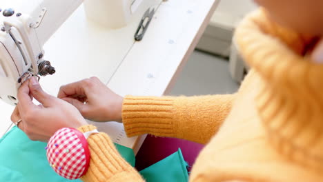 Biracial-female-fashion-designer-threading-sewing-machine-in-studio,-slow-motion