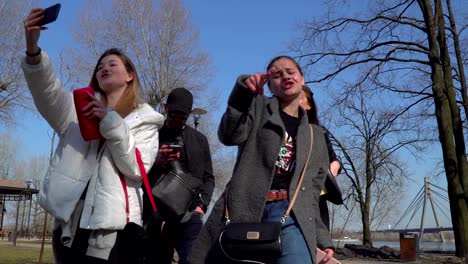 adolescentes se disparan a sí mismos en el teléfono mientras cantan y bailan en el parque