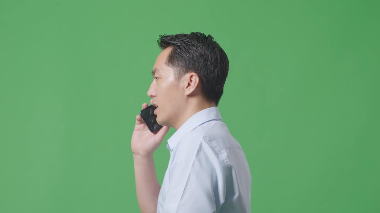 스튜디오의 녹색 화면 배경에서 는 동안 휴대 전화로 이야기하는 아시아 사업가의 측면 뷰 클로즈업