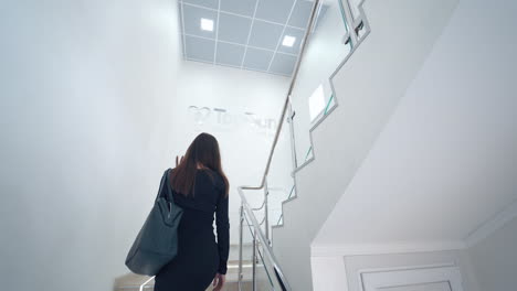 woman indoors on the stairs. back view of young woman walking up the stairs