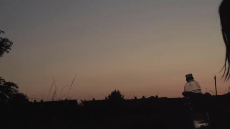 alone woman silhouette drinking bottle of water at sunset-1