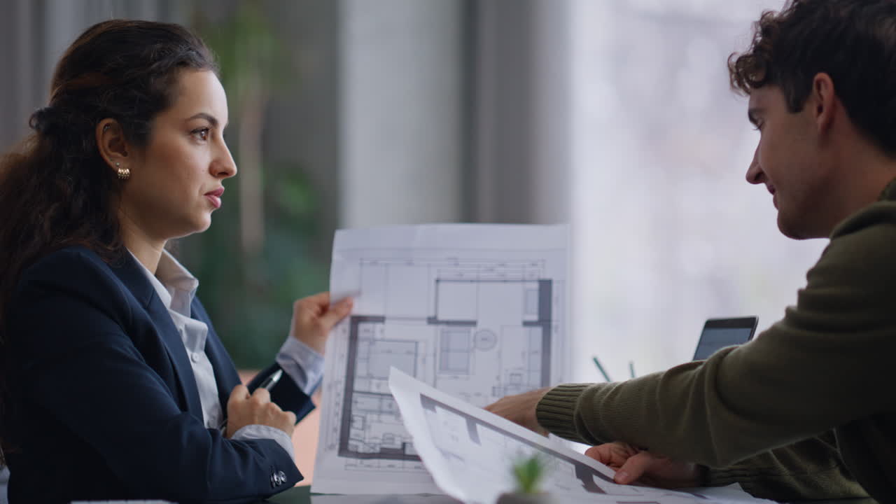 Professional technician consulting customer showing draft in office closeup